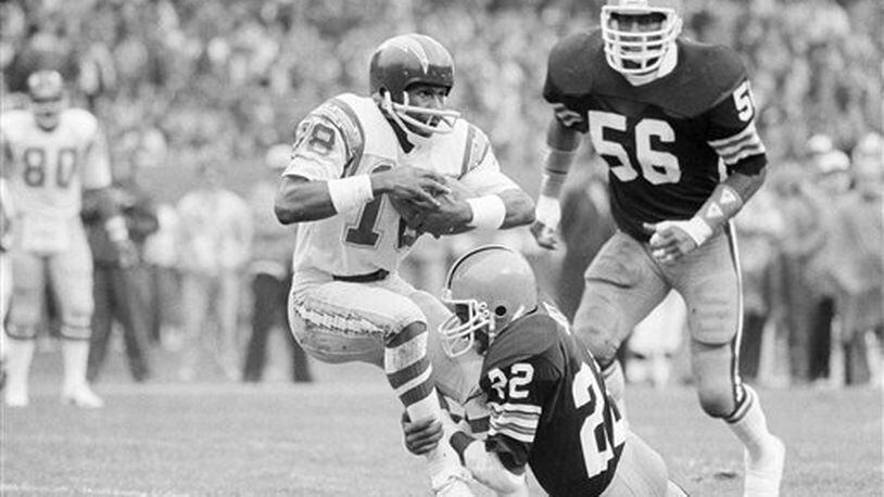 San Diego Chargers receiver Charlie Joiner (18) is dragged down by Cleveland Browns defender Clarence Scott after a catch in the first quarter of the game in Cleveland Stadium, Dec. 5, 1982. Coming up from behind is Browns' linebacker Chip Banks (56).  (AP Photo/Bruce Zake)