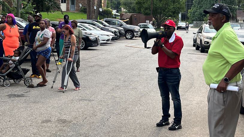 DeKalb County Commissioner Larry Johnson, at right with megaphone, speaks to a crowd of residents of the Forest at Columbia apartments during an event on Monday, Aug. 15.