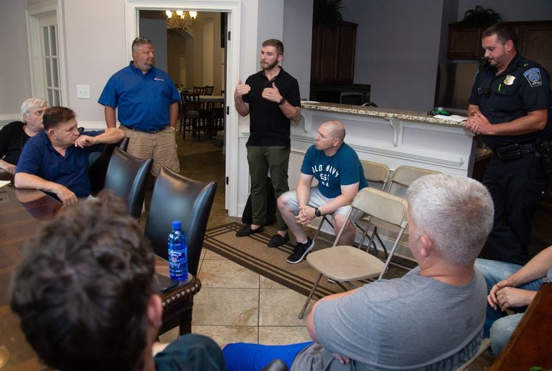 Flock Safety representative Ben Francis (center) talks with residents of the McGinnis Reserve community about their newly install surveillance license plate camera Monday, July 29, 2019. STEVE SCHAEFER / SPECIAL TO THE AJC