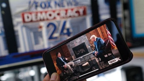 A photo illustration shows a preview on a smartphone of Tucker Carlson's interview of former President Donald Trump scheduled to air on X, formerly Twitter, on the same night of the first Republican Presidential primary debate in Milwaukee on Wednesday, Aug. 23, 2023. (Chris Delmas/AFP/Getty Images/TNS)