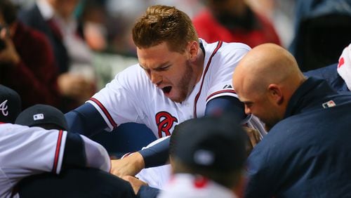 Freddie Freeman, Brian McCann and the rest of the Braves bury catcher Evan Gattis under a pile in the dugout after his solo home run in the fourth inning Wednesday against the Phillies.