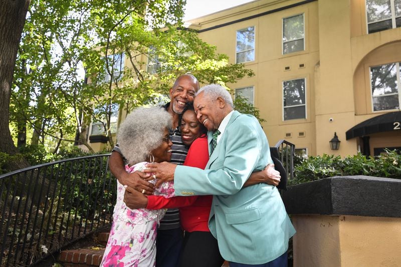 Debra Biagini (pictured in red) gets a group hug from her father, Ambassador Theodore Britton Jr. (right), and her siblings Warren and Renee outside Britton’s apartment building in Atlanta last Saturday. CONTRIBUTED BY JOHN AMIS