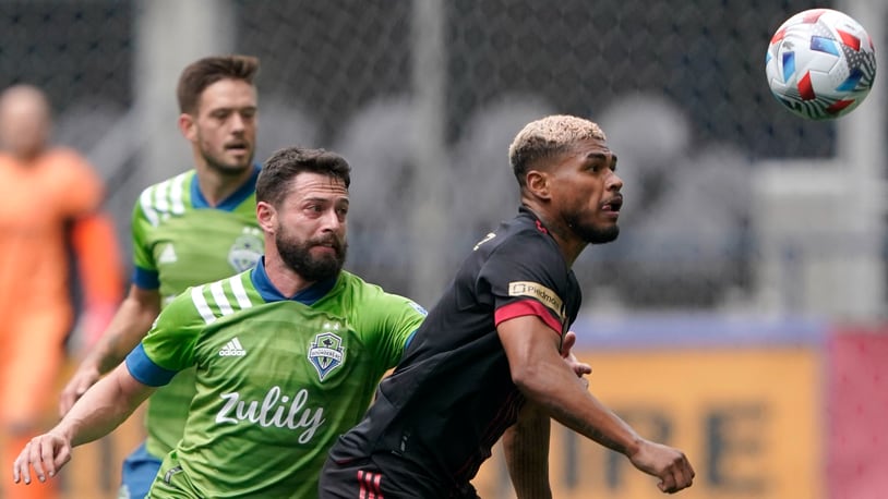 Atlanta United forward Josef Martinez, right, and Seattle Sounders midfielder Joao Paulo, center, watch the ball during the first half of an MLS soccer match, Sunday, May 23, 2021, in Seattle. (AP Photo/Ted S. Warren)