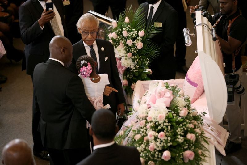 081122 Atlanta, Ga.: Rev. Al Shaprton, top center, talks with one of the two daughters of Brianna Grier as she is held by a family member as they view the open casket during the celebration of life for Brianna Grier at West Hunter Street Baptist Church, Thursday, August 11, 2022, in Atlanta. Grier is the woman who died after Hancock Police officers left the door open on the back of the police car after arresting her. (Jason Getz / Jason.Getz@ajc.com)
