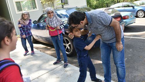 Yaser Musa kisses his son, Issa, 5, outside their Clarkston apartment as he waits for his other children (from left) Samar, 10, Nor Alhoda, 12, and Reem, 11, on April 13, 2017. HYOSUB SHIN / HSHIN@AJC.COM