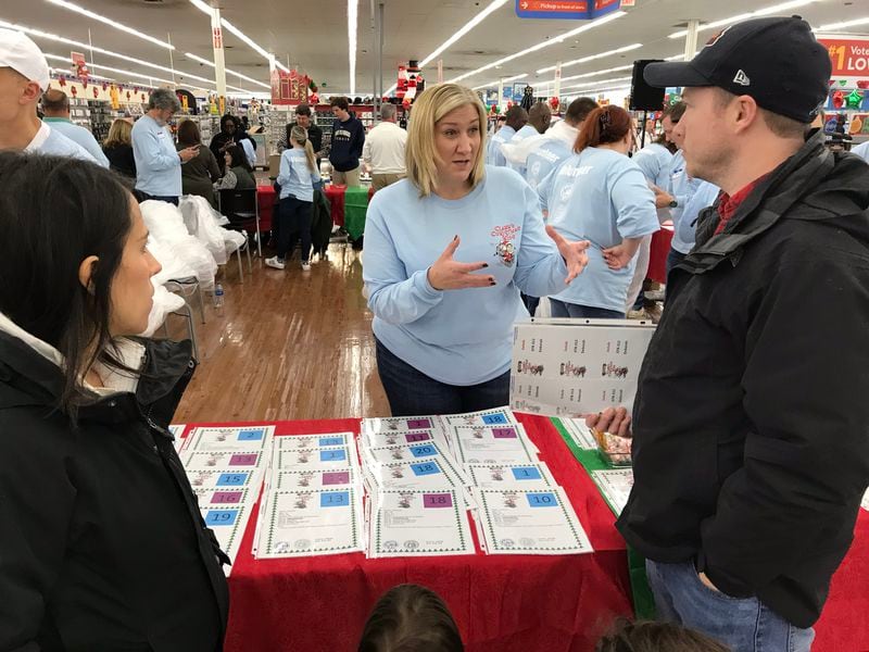 Stacey Felzer, center, is volunteering for the first time for Clark's Kids, guiding shoppers on how the system works. CREDIT: Rodney Ho/rho@ajc.com