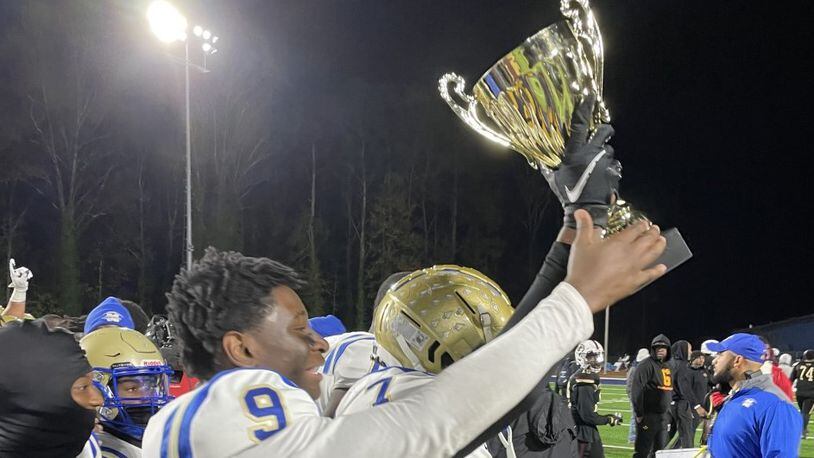 McEachern players celebrate with the championship trophy after defeated Pebblebrook 33-20 to win the Region 2-7A title on Nov. 5, 2021