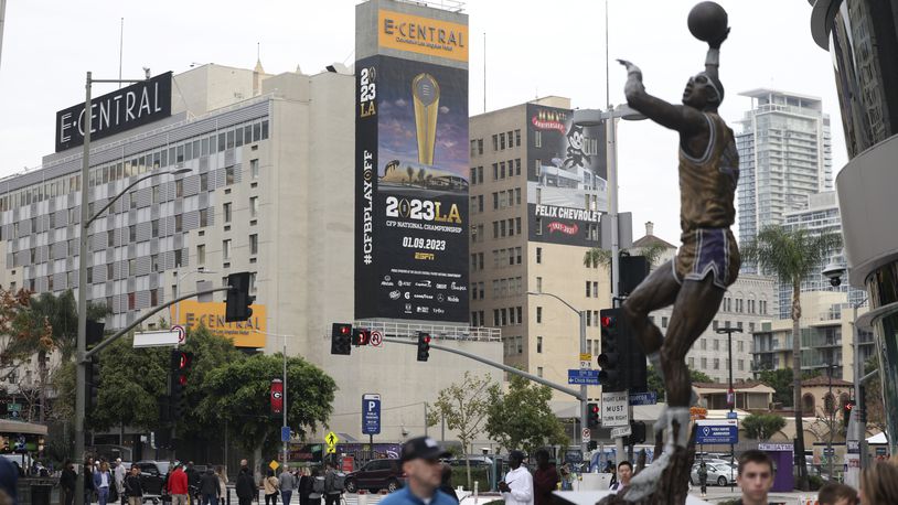 A billboard for the 2023 College Football Playoff National Championship game is shown near a statue of LA Lakers great Kareem Abdul-Jabbar at Crypto.com Arena, Sunday, Jan. 8, 2023, in Los Angeles, Calif. Georgia plays TCU for the 2023 College Football Playoff National Championship Mon. Jan. 9, 2023, at SoFi Stadium.  (Jason Getz / Jason.Getz@ajc.com)