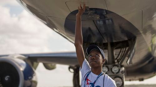 7/16/2019 -- Pensacola, Florida -- Camden Military Academy student and ACE camp participant Malik Williams strokes his hand under the belly of a Delta Air Lines plane after landing at Naval Air Station Pensacola during the 20th annual Delta Air Lines' "dream flight" aviation Summer camp, Tuesday, July 16, 2019. (Alyssa Pointer/alyssa.pointer@ajc.com)