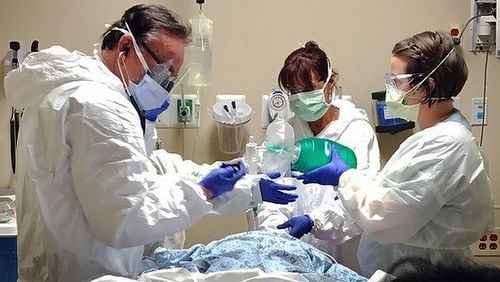 Drs. Joseph Funk and Kathleen Funk and RN Sara Tettelbach are in full personal protective equipment as they care for a critical patient at Northside Hospital amid rising COVID-19 cases. CONTRIBUTED PHOTO