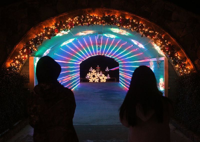 A pair of visitors take in the festive light display in a tunnel at Margaritaville in Lanier Islands in Buford. Curtis Compton/ccompton@ajc.com
