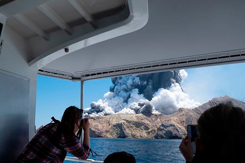Tourists on a boat observe the Monday eruption of the volcano on White Island, New Zealand. Unstable conditions continued to hamper rescue workers from searching for people missing and feared dead.