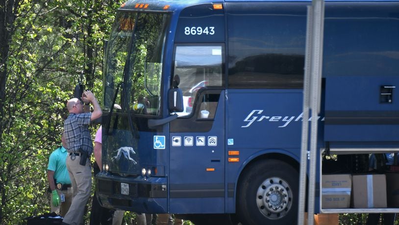 An officer tries to look inside a Greyhound bus through the windshield after an armed man was taken into custody on an I-85 on-ramp in Gwinnett County on Tuesday.
