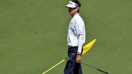 Bubba Watson holds the flag on the No. 2 green at Augusta National Golf Club. The former Georgia golfer struggled on the greens Friday, shooting a 6-over 78 and finishing the first two days at 8 over par, missing the cut at the Masters. (Brant Sanderlin/Special)