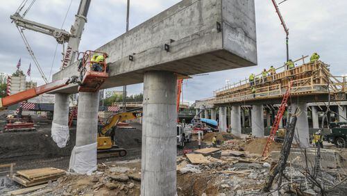 Construction workers continued to reshape the I-85 bridge Monday, working high on the pillar supports as bridge beams were starting to arrive. JOHN SPINK/JSPINK@AJC.COM