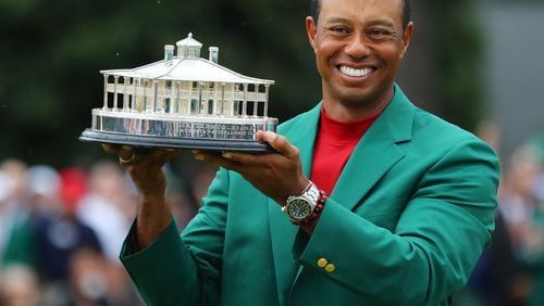 Tiger Woods holds the trophy after being presented the green jacket for winning the Masters in 2019 at Augusta National Golf Club. Woods  is undecided about playing in this year's event. (Curtis Compton/ccompton@ajc.com)