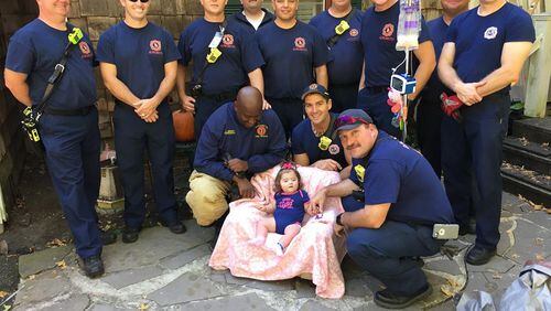 Multiple members of the Alpharetta Fire Department surround 11-month-old Raven Nell Raines outside of her home on Sherry Lane.