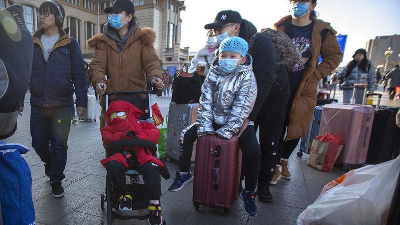 Travelers wear face masks as they walk outside of the Beijing Railway Station in Beijing, Monday, Jan. 20, 2020. China reported Monday a sharp rise in the number of people infected with a new coronavirus, including the first cases in the capital. The outbreak coincides with the country’s busiest travel period, as millions board trains and planes for the Lunar New Year holidays. (AP Photo/Mark Schiefelbein)