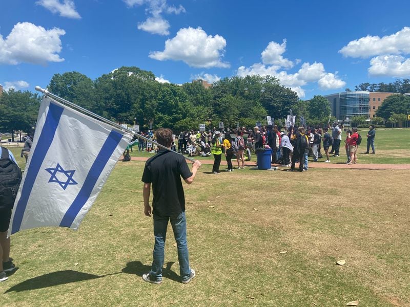 Kennesaw State University sophomore Aaron Weinberg carries an Israeli flag as pro-Palestinian demonstrators rally on the Campus Green.
