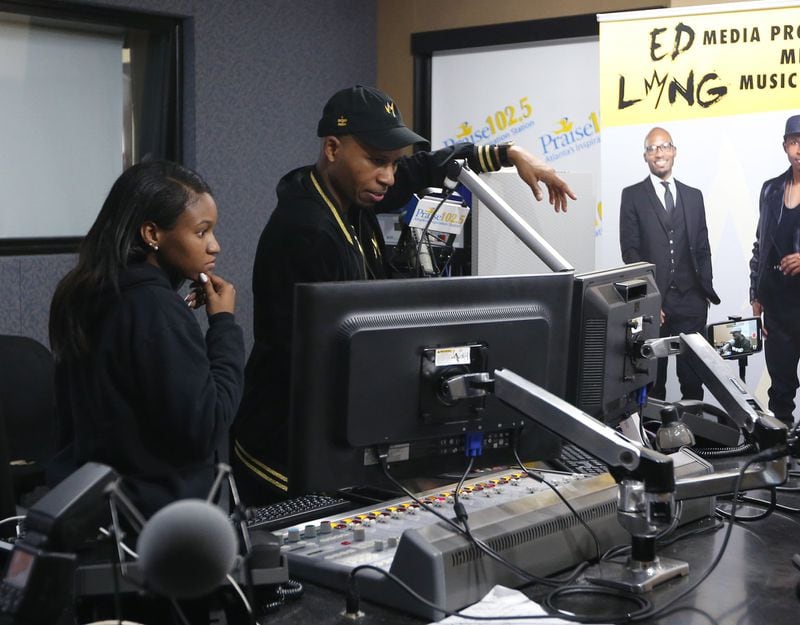 Bre Singleton (left) and Edward Long look over content during a break on his radio show on Praise 102.5. in Atlanta. EMILY HANEY / EMILY.HANEY@AJC.COM