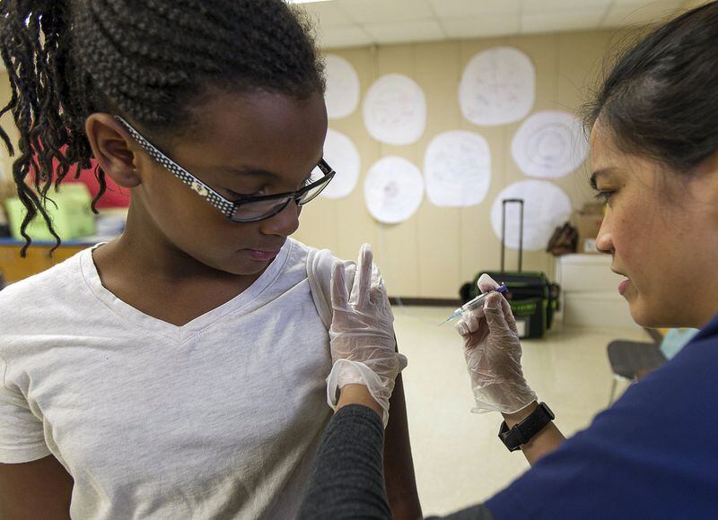 Get your shots up to date before school starts. Rhema Colvin, 9, gets a flu shot vaccination from RN Catherine Calimlim.