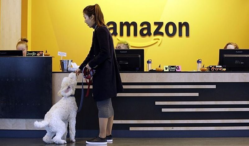 An Amazon employee gives her dog a biscuit as the pair heads into a company building, where dogs are welcome, in Seattle. Butler County's Liberty township is making efforts to snag Amazon's second North American headquarters.