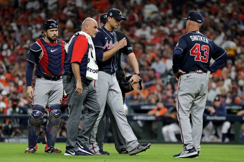 Braves starting pitcher Charlie Morton walks off of the mound with an athletic trainer as manager Brian Snitker (43) checks in on pitcher as he exits Game 1 of the World Series during the third inning Tuesday Oct. 26, 2021, in Houston. Morton suffered a broken fibula pitching against the Astros. (Curtis Compton / curtis.compton@ajc.com)