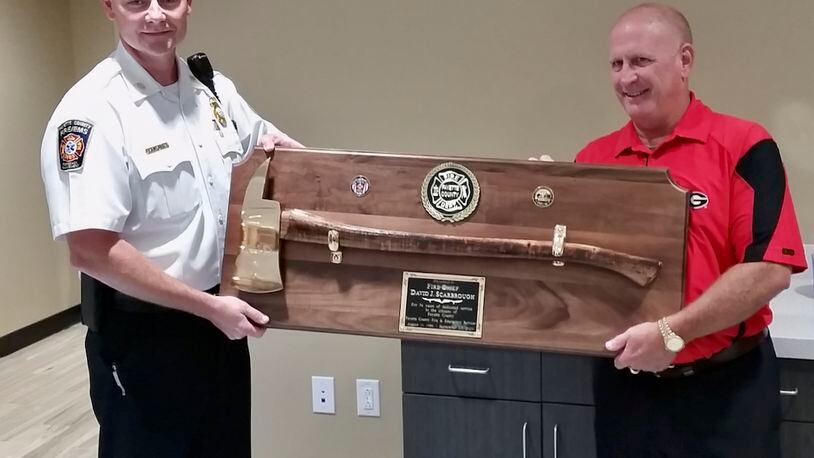 Interim Fayette County Fire Chief Jeff Hill presented retiring chief David Scarbrough with a commemorative axe noting Scarbrough's 34 years of service to the county. Courtesy Fayette County
