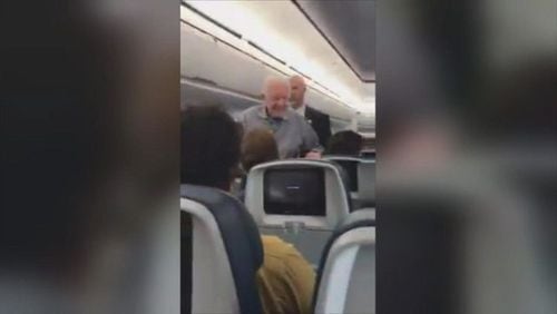 Former President Jimmy Carter works his way down the aisle, shaking passenger’s hands, on a flight last week.