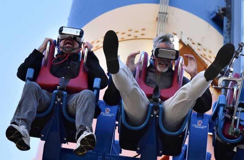 The AJC’s Tom Kelley (right) and Tim Baldwin (left), communications director of the American Coaster Enthusiasts, ride Drop of Doom VR, a new virtual reality version of the Acrophobia drop tower, at Six Flags Over Georgia this week. Using Samsung Gear VR powered by Oculus, riders become the pilots of a futuristic gunship under attack by mutant spiders. Drop of Doom VR debuts Saturday, March 11, when Six Flags Over Georgia opens for the season. HYOSUB SHIN / HSHIN@AJC.COM