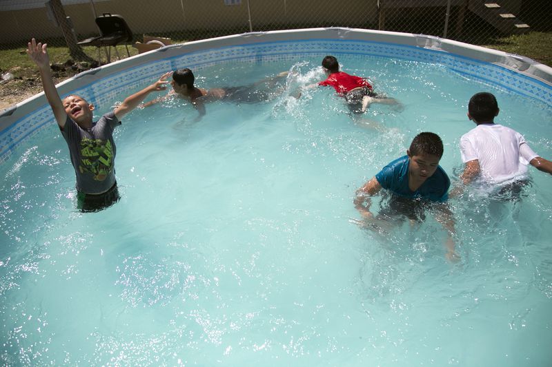 On March 26, 2017, (left to right) Esteban Espinosa, Sean Flores, Rogelio Espinosa, Julian Madrigal and Juan Carlos Madrigal swam in a make-shift pool between a row of uniform white trailers housing Kickapoo families on their reservation south of Eagle Pass, Texas. Originally from the Great Lakes region, the Kickapoo Traditional Tribe of Texas also has reservations in northern Mexico, which they visit frequently. Adriana Flores, mother to all seven children,  thinks that President Donald Trump is currently motivated to extend the border wall because of racial prejudice. 