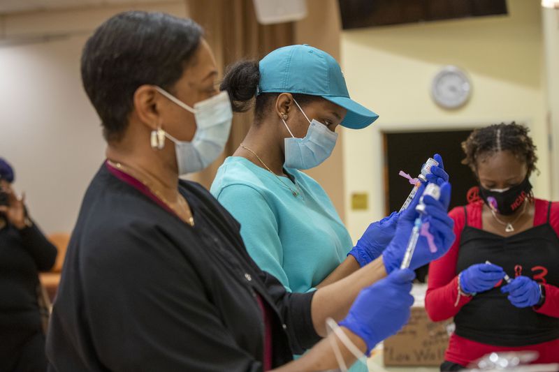 Οι εγγεγραμμένοι νοσοκόμες Ashanit Booker, Center, Arnita Dunwell ετοιμάζουν ένα εμβόλιο COVID-19 κατά τη διάρκεια μιας εκδήλωσης εμβολιασμού που δημιουργήθηκε από το Συμβούλιο Υγείας της DeKalb County και την Delta Sigma Theta Sorority Inc.  (Alyssa Pointer / Alyssa.Pointer@ajc.com)