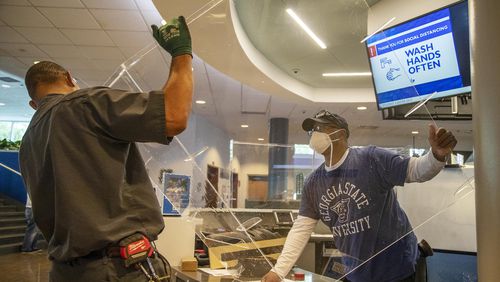 08/24/2020 - Atlanta, Georgia - Georgia State University Cabinet Shop Supervisor Barry Coombs (right) and Georgia State University Carpenter Ivan Franklin (left) place a plastic shield on the information desk inside the Student Center during the first day of classes at Georgia State University in Atlanta, Monday, August 24, 2020. (ALYSSA POINTER / ALYSSA.POINTER@AJC.COM)