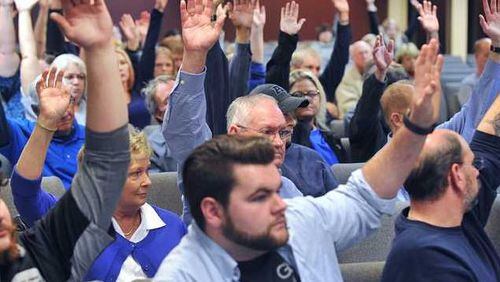Those opposed to a rezoning request by Straight Street Revolution Ministries raised their hands Monday. (Credit: The Gainesville Times)