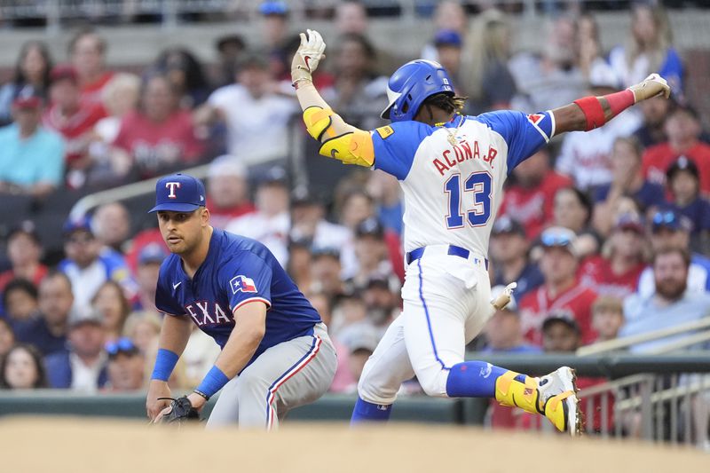 Atlanta Braves' Ronald Acuña Jr. (13) is safe at first base with a single as Texas Rangers first baseman Nathaniel Lowe waits for the late throw in the first inning of a baseball game Saturday, April 20, 2024, in Atlanta. (AP Photo/John Bazemore)