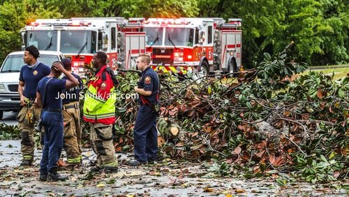 Firefighters on Guilford Forest Drive survey the damage after a severe storm swept through the city Monday morning.