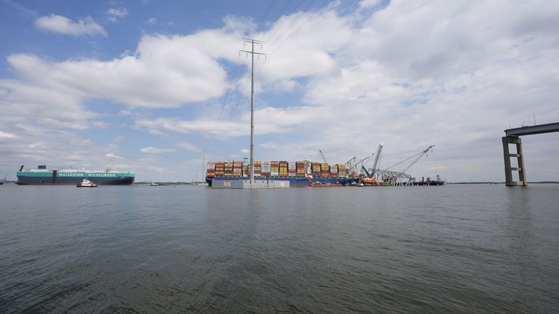 A vessel, left, moves past the stranded container ship Dali, through a newly opened deep-water channel in Baltimore after being stuck in the harbor since the Francis Scott Key Bridge collapsed four weeks ago, Thursday, April 25, 2024. (AP Photo/Matt Rourke)