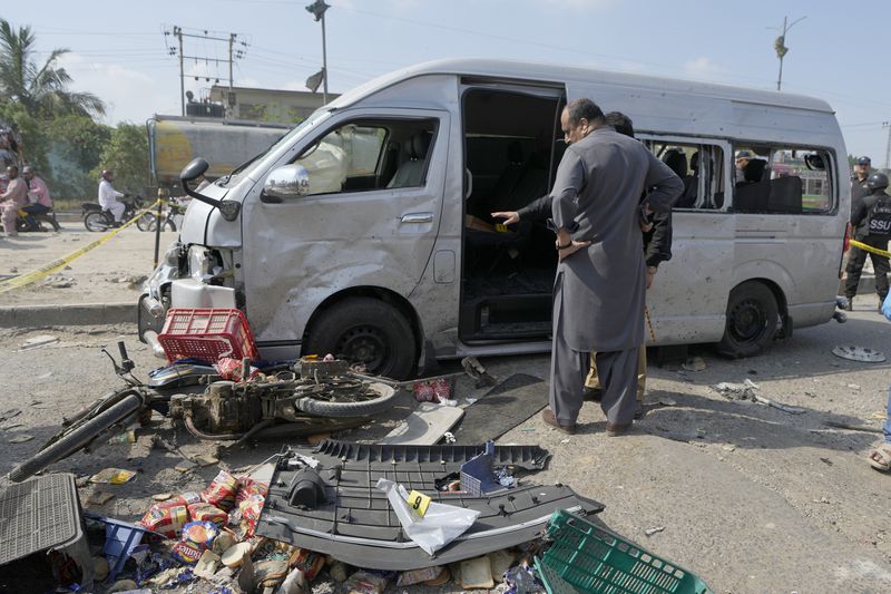 Pakistani investigators examine a damaged van at the site of a suicide attack in Karachi, Pakistan, Friday, April 20, 2024. Five Japanese nationals traveling in a van narrowly escaped a suicide attack when a suicide bomber detonated his explosive-laden vest near their vehicle in Pakistan's port city of Karachi on Friday, wounding three passers-by, police said. (AP Photo/Fareed Khan)
