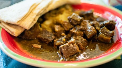 The bone-in curry goat combination meal with warm roti at Tassa Roti Shop in Marietta. CONTRIBUTED BY HENRI HOLLIS