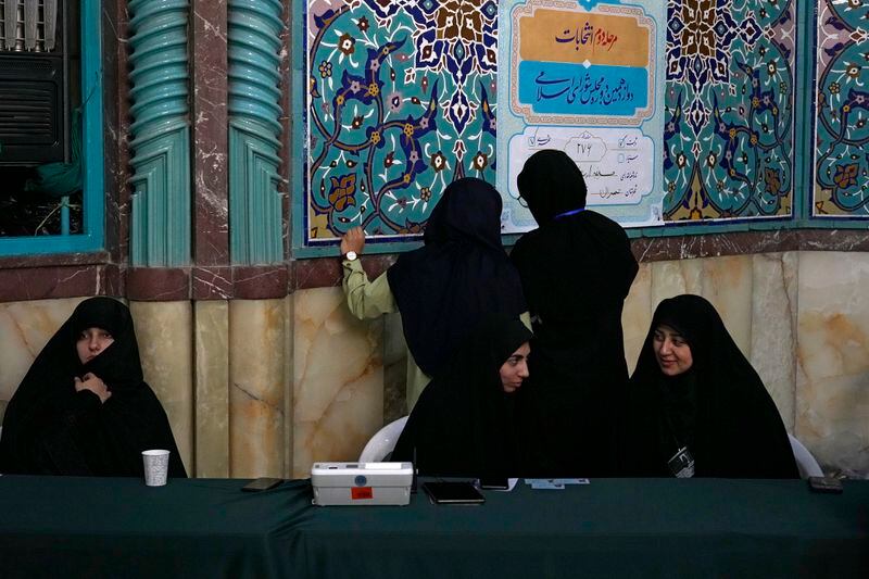 Staff members of a polling station attend to their stations during the parliamentary runoff elections in Tehran, Iran, Friday, May 10, 2024. Iranians voted Friday in a runoff election for the remaining seats in the country's parliament after hard-line politicians dominated March balloting. (AP Photo/Vahid Salemi)