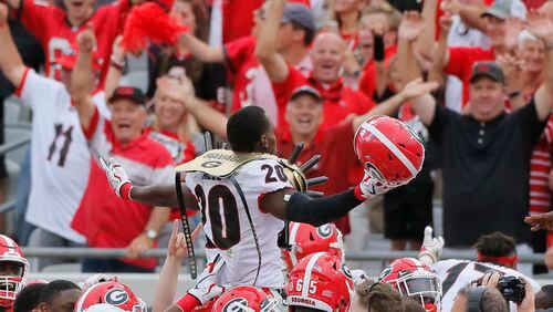 Georgia defensive back J.R. Reed (20) is lifted above his teammates after he scored on a sack and fumble by Florida's quarterback during the Bulldogs' 42-7 win in Jacksonville, Fla. (Bob Andres/bandres@ajc.com)