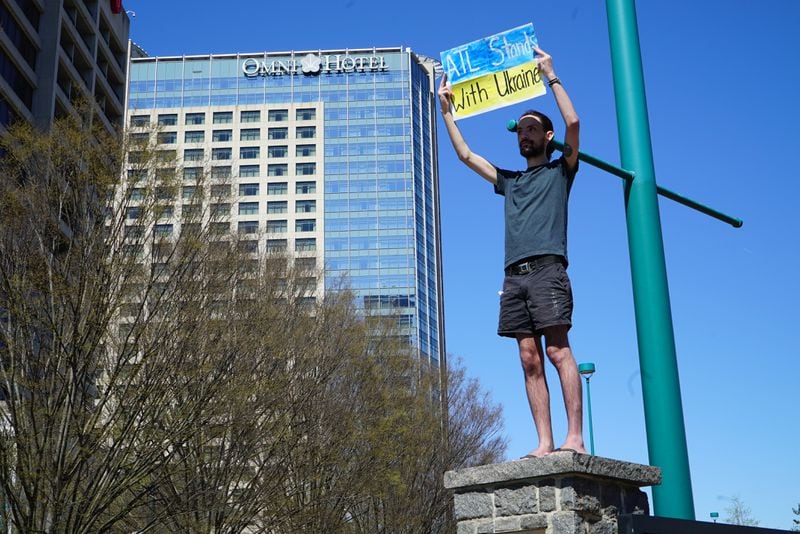 A protester climbs on a column outside Centennial Olympic Park at a rally on Saturday, March 19, 2022 to raise awareness about the plight of children in the war in Ukraine. Some called for the establishment of a no-fly zone over the country.