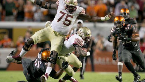 Florida State Seminoles running back Dalvin Cook (4) runs into his blocker offensive tackle Cameron Erving (75) as he is tackled by Miami Hurricanes linebacker Denzel Perryman (52) at Sun Life Stadium in Miami Gardens, Florida on November 15, 2014. (Allen Eyestone / The Palm Beach Post)