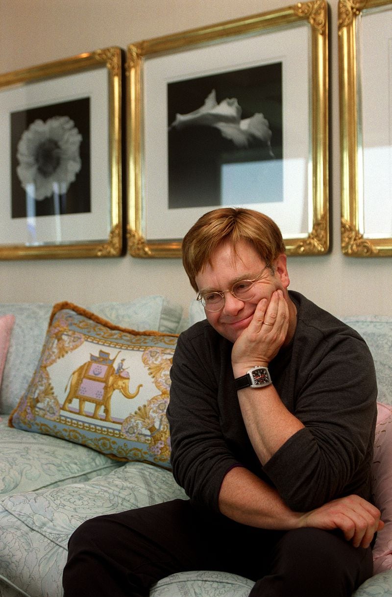 Elton John relaxes in his Atlanta condo in 2000 while discussing his photography collection. Behind him are black and white photographs by Robert Mapplethorpe. (JEAN SHIFRIN/staff)
