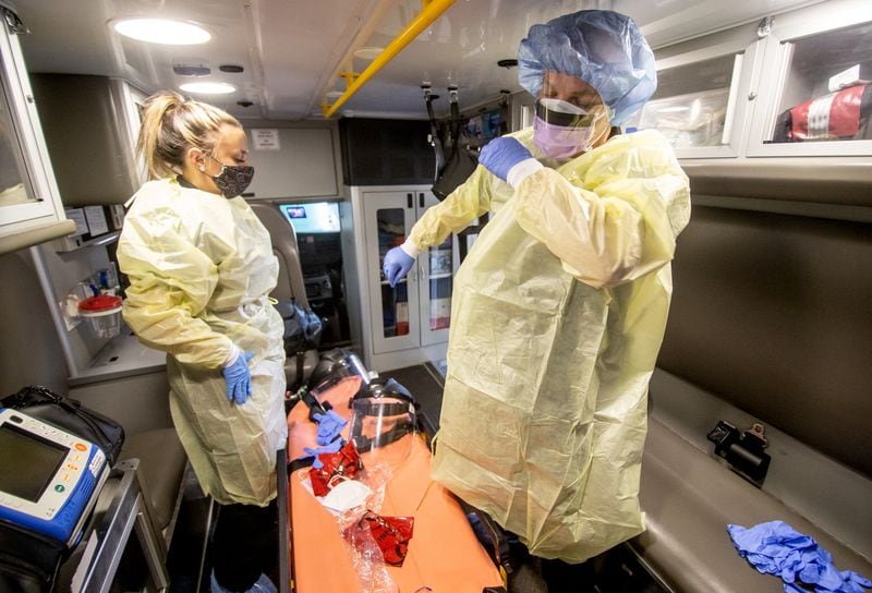 EMT Maci Williams, left, and Paramedic Christopher Kozinski demonstrate how they put on their personal protective equipment before every call at the Central EMS office in Roswell July 16, 2020.  (STEVE SCHAEFER FOR THE ATLANTA JOURNAL-CONSTITUTION)