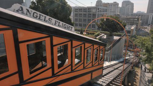 This Wednesday, Aug. 30, 2017, photo shows a pedestrian walking a steep flight of stairs next to the Angels Flight railroad in downtown Los Angeles. The 298-foot funicular, closed since a 2013 derailment, reopened Thursday, Aug. 31, just in time to ferry thousands of holiday weekend visitors up and down downtown's steep Bunker Hill, something it first did on New Year's Eve 1901.