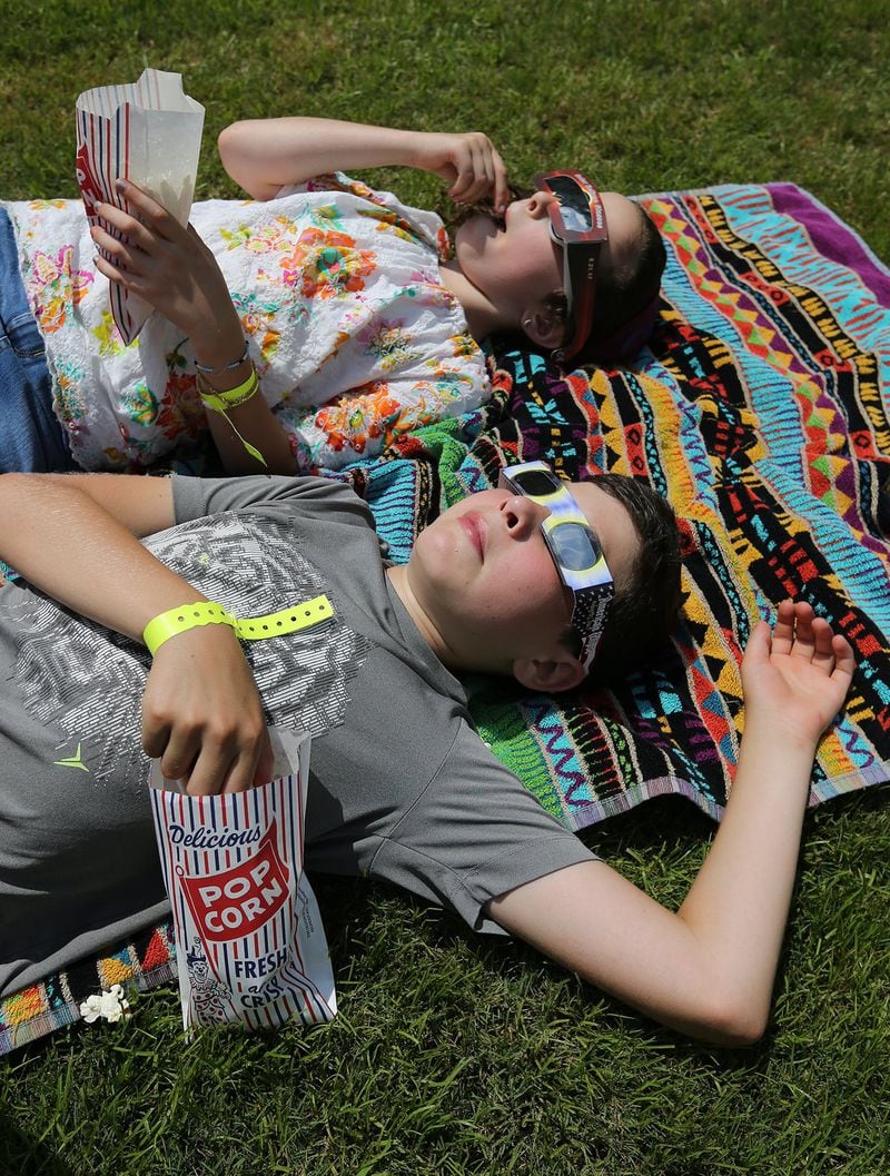 Popcorn and a total solar eclipse viewing make for an afternoon of entertainment for Meir Straus, 12, and his sister Isla, 9, who came all the way from Toronto to Rabun Countyfor the experience. CURTIS COMPTON / CCOMPTON@AJC.COM