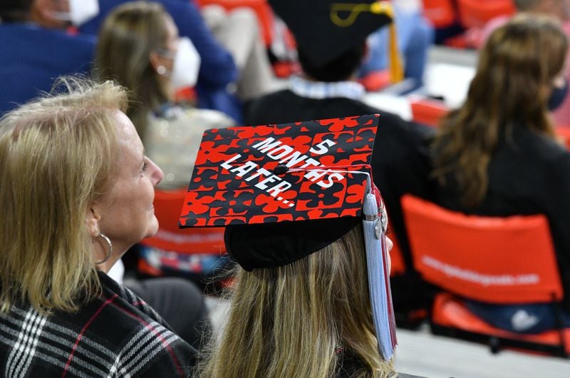 October 16, 2020 Athens - A UGA graduate decorated her  cap with a message saying Ò5 Month Later,Ó which the commencement delayed for 5 months, as graduates and their families stay in the stands during the 2020 Spring Undergraduate Commencement ceremony at Sanford Stadium in Athens on Friday, October 16, 2020. (Hyosub Shin / Hyosub.Shin@ajc.com)