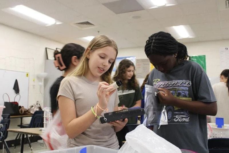 Dickerson Middle School students Rori Smith and Aria Tettey are members of the Pay It Forward club. Here, they pack bags of toiletries for families staying in Ronald McDonald Houses in Atlanta. (Photo Courtesy of Annie Mayne/Marietta Daily Journal)