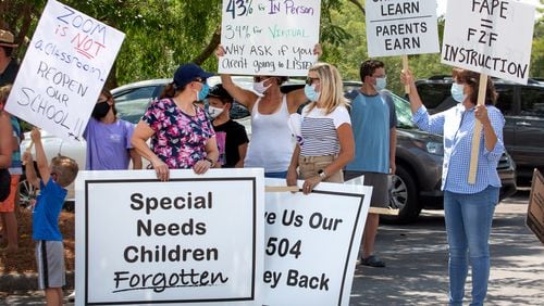 Michelle Russell, left, and Stacey Dickinson, center, hold signs supporting special needs children during a demonstration at the Gwinnett Instructional Support Center in Suwanee on July 27.  STEVE SCHAEFER FOR THE ATLANTA JOURNAL-CONSTITUTION